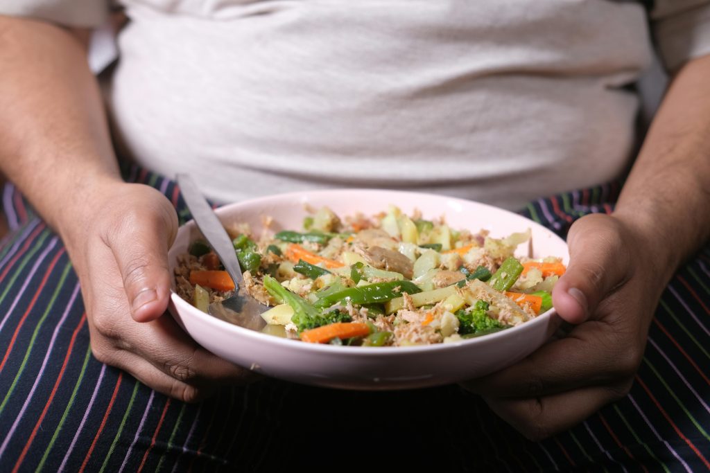 Overweight man holding a plate of food