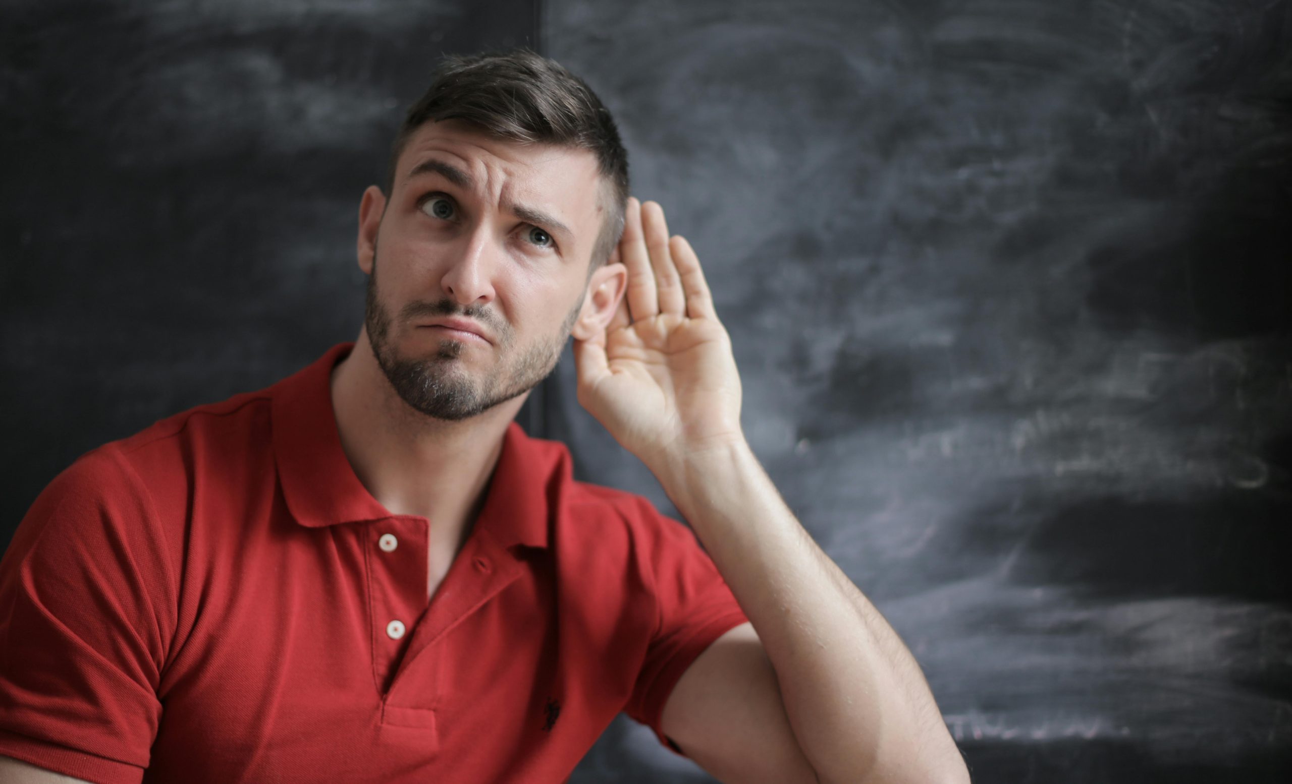 Man with his hand to his ear listening